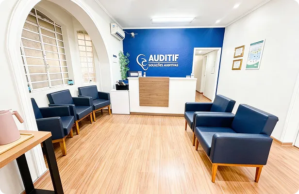 Fonoaudióloga sorridente examinando o ouvido de um paciente idoso com otoscópio em consultório clínico moderno, paleta azul-marinho e dourado suave, iluminação natural acolhedora, fotografia profissional realista